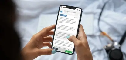 Mão segurando um celular com a Plataforma de Questões Comentadas OAB aberta