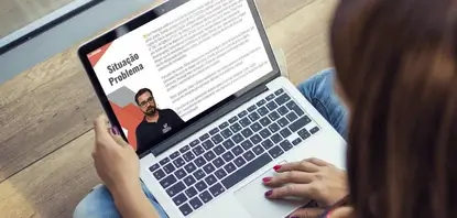 Mulher branca com um notebook no colo enquanto assiste uma aula do Curso para 2ª fase da OAB